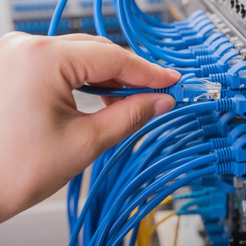 man connecting network cable to switch